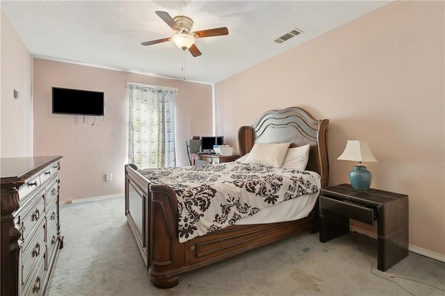 bedroom featuring visible vents, baseboards, light colored carpet, a textured ceiling, and a ceiling fan