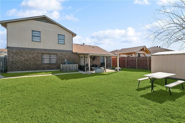 back of property featuring a fenced backyard, a yard, an outdoor structure, brick siding, and a patio area