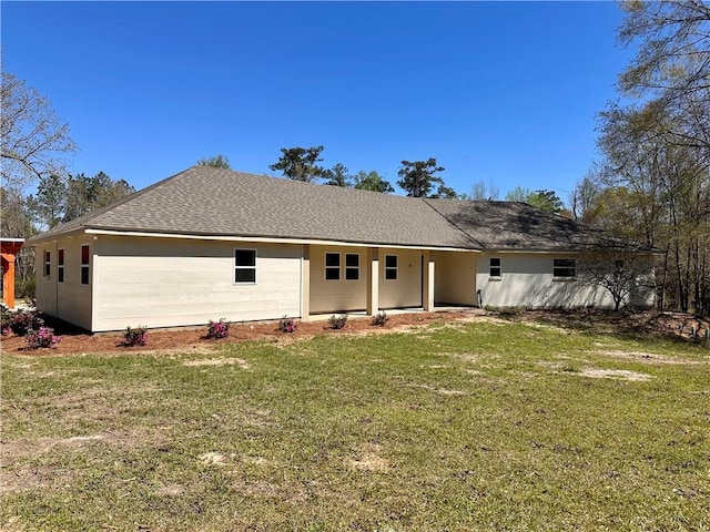 rear view of house with a shingled roof and a yard