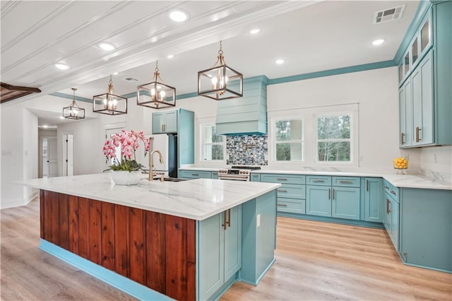 kitchen with blue cabinetry, visible vents, stainless steel range, and light wood-type flooring