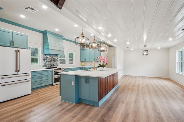 kitchen with a sink, visible vents, custom exhaust hood, premium appliances, and blue cabinetry