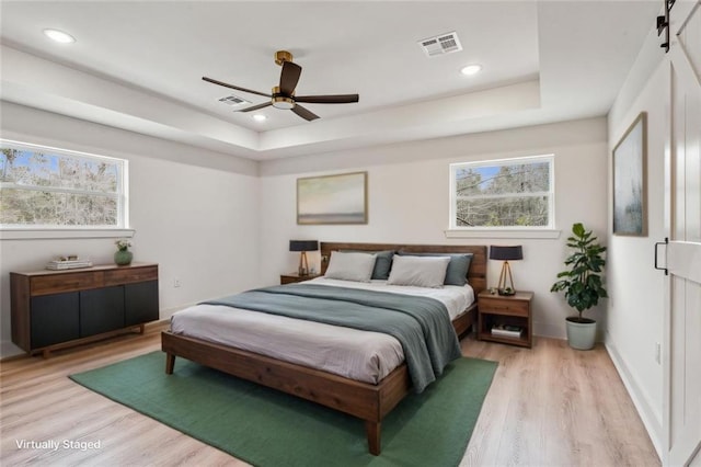 bedroom featuring multiple windows, visible vents, and a raised ceiling
