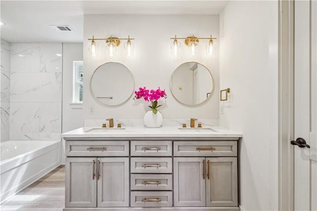 bathroom featuring a tub to relax in, visible vents, a sink, and double vanity