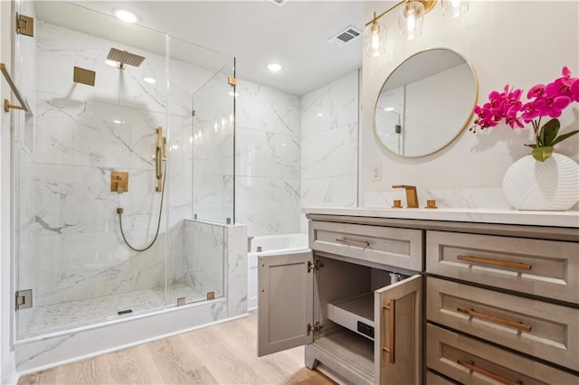 bathroom with wood finished floors, a marble finish shower, vanity, visible vents, and recessed lighting