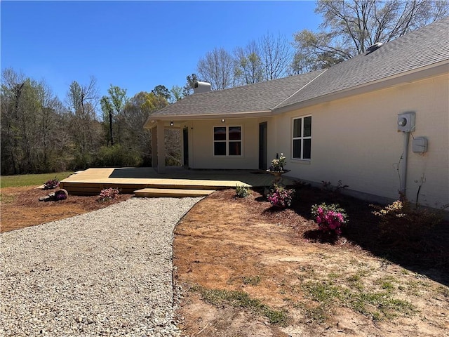 entrance to property featuring a deck and a shingled roof