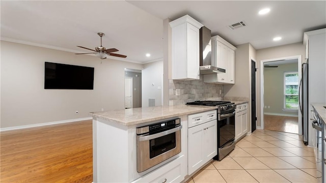 kitchen featuring visible vents, ceiling fan, stainless steel appliances, wall chimney exhaust hood, and tasteful backsplash