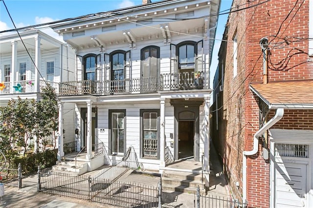 italianate house with a balcony, a gate, and a fenced front yard