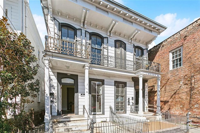 view of front of house featuring a fenced front yard, a balcony, and a porch