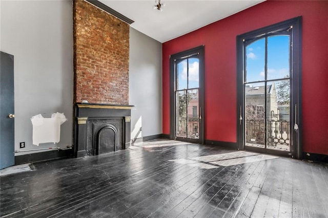 unfurnished living room featuring a fireplace, baseboards, and wood-type flooring