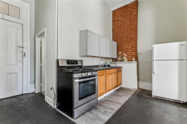 kitchen with wood finished floors, gas stove, freestanding refrigerator, a sink, and dark countertops