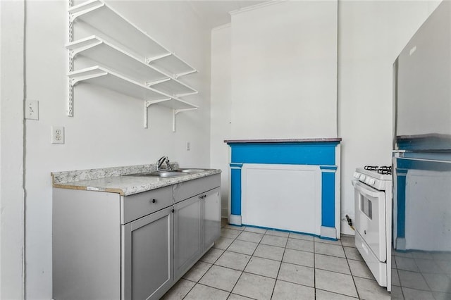 kitchen featuring white range with gas cooktop, gray cabinets, open shelves, a sink, and light tile patterned floors