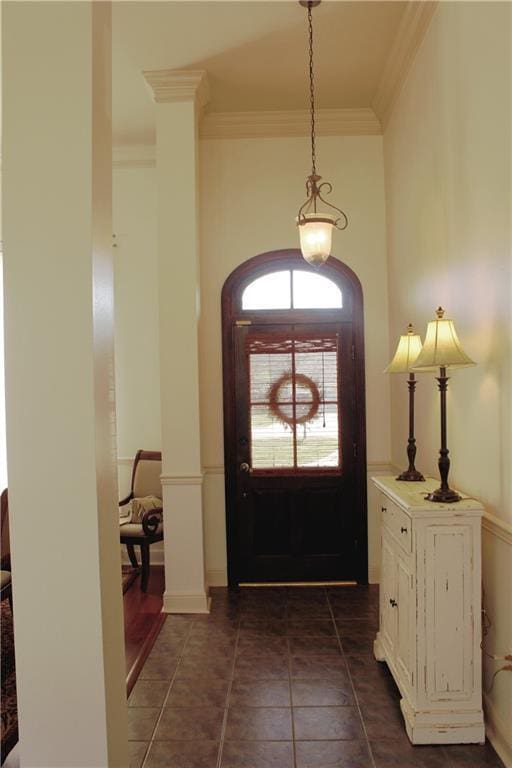 foyer entrance with dark tile patterned floors and ornamental molding