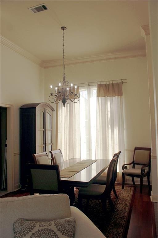 dining room with dark wood-style floors, visible vents, crown molding, and an inviting chandelier