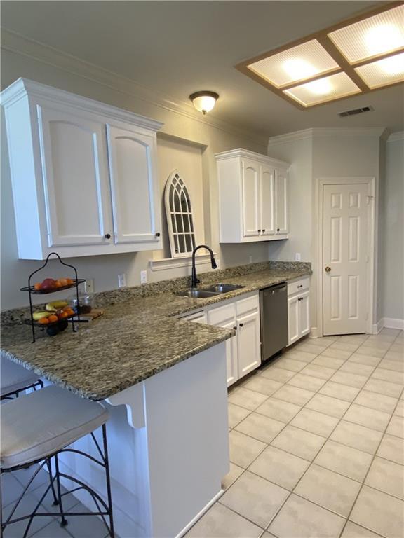 kitchen featuring a peninsula, ornamental molding, a sink, white cabinets, and dishwasher