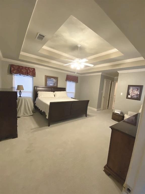 bedroom featuring visible vents, light colored carpet, crown molding, and a tray ceiling