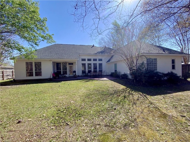 rear view of property featuring a yard, a patio, a shingled roof, and fence