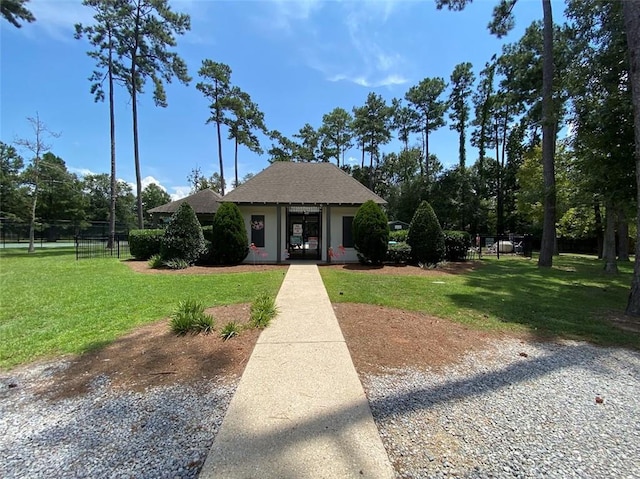 view of front of property with a shingled roof, a front lawn, and fence