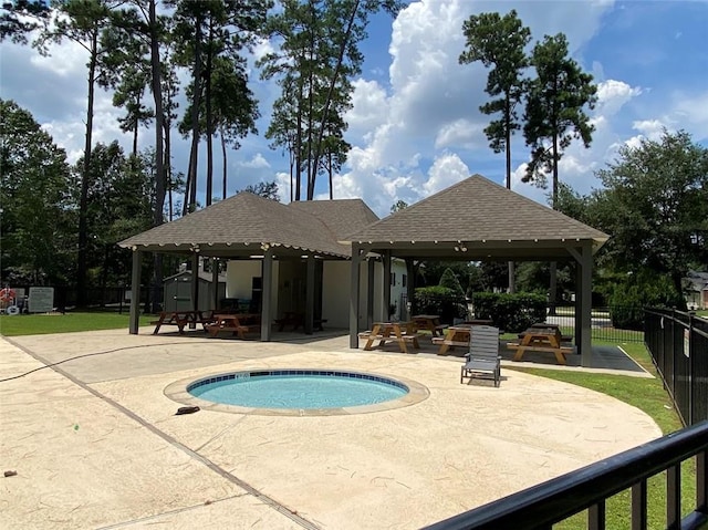 view of swimming pool featuring a patio, fence, an in ground hot tub, a gazebo, and a storage unit