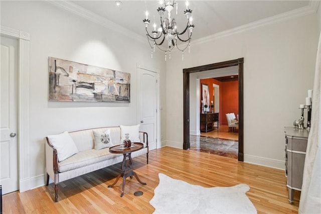 living area with a notable chandelier, light wood-style floors, baseboards, and ornamental molding