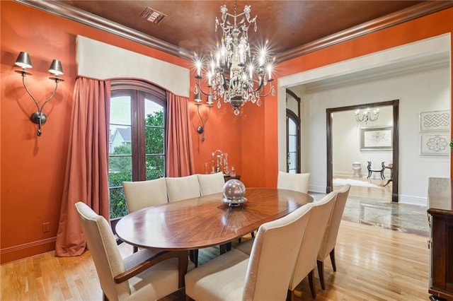 dining room with light wood finished floors, a notable chandelier, baseboards, and ornamental molding