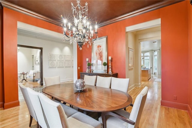 dining room with a chandelier, light wood-type flooring, baseboards, and ornamental molding