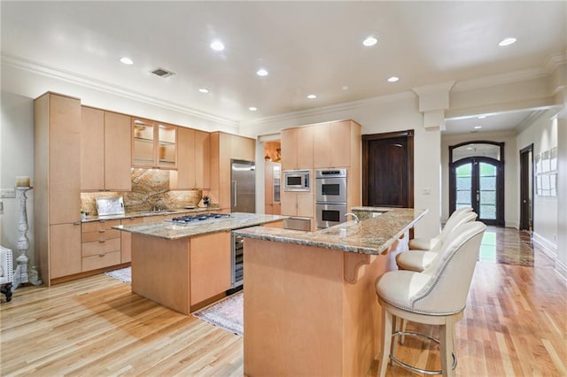 kitchen featuring visible vents, an island with sink, a kitchen breakfast bar, french doors, and appliances with stainless steel finishes