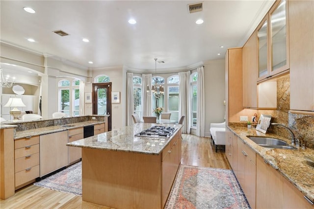 kitchen with visible vents, a sink, a center island, stainless steel gas stovetop, and light wood finished floors