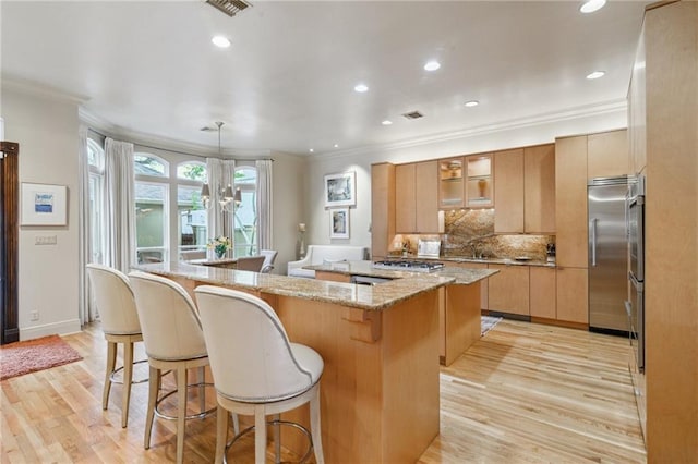 kitchen with a spacious island, appliances with stainless steel finishes, a breakfast bar area, and ornamental molding