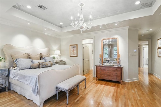 bedroom featuring visible vents, a tray ceiling, light wood finished floors, baseboards, and a chandelier