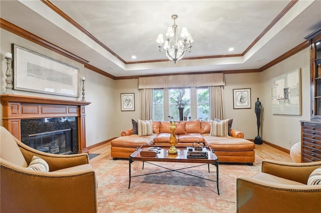 living room with a tray ceiling, wood finished floors, a high end fireplace, and a chandelier