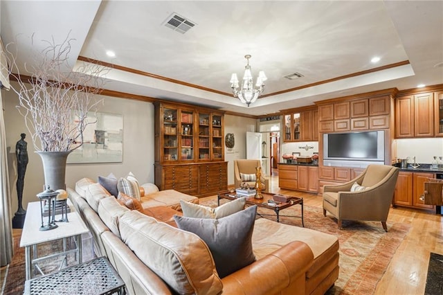 living room featuring light wood finished floors, visible vents, a raised ceiling, and an inviting chandelier