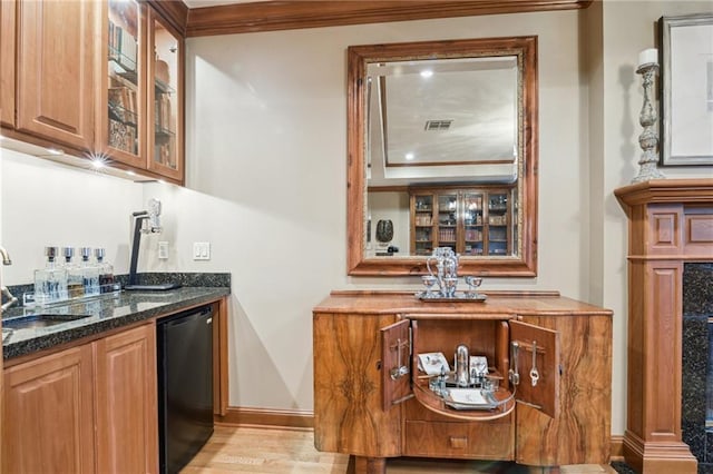 bar with baseboards, a sink, indoor wet bar, dishwasher, and light wood-type flooring