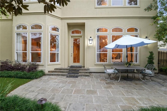 view of exterior entry featuring stucco siding and a patio area