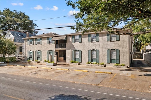 view of front facade with uncovered parking and brick siding