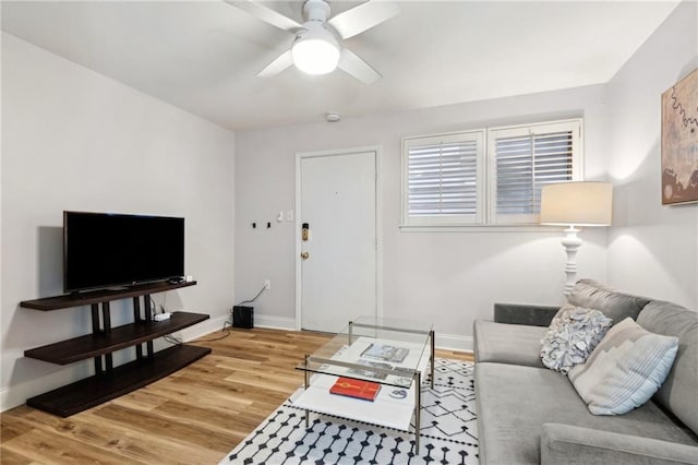 living room featuring light wood-style flooring, baseboards, and a ceiling fan