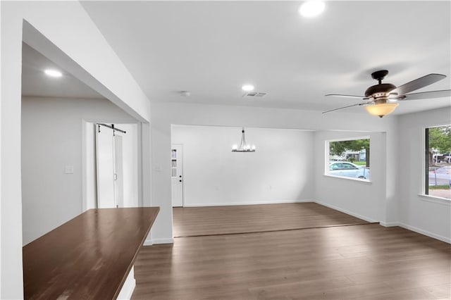 365 Olive Dr, Slidell, LA 70458 - unfurnished dining area with a barn door, baseboards, wood finished floors, and ceiling fan with notable chandelier
