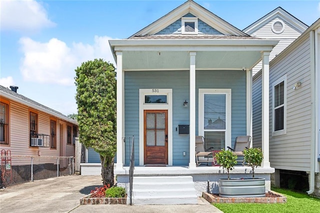 entrance to property featuring covered porch and fence