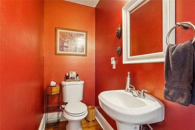 half bathroom featuring toilet, a sink, and baseboards