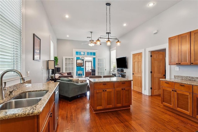 kitchen featuring a sink, open floor plan, a ceiling fan, brown cabinets, and a kitchen island