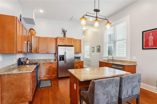 kitchen with a sink, dark wood finished floors, light stone counters, and stainless steel appliances
