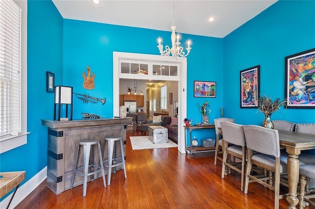dining area with plenty of natural light, baseboards, an inviting chandelier, and wood finished floors