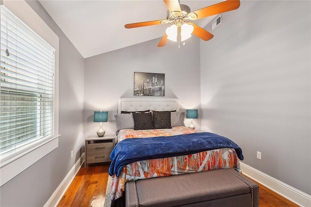 bedroom featuring visible vents, baseboards, vaulted ceiling, and wood finished floors