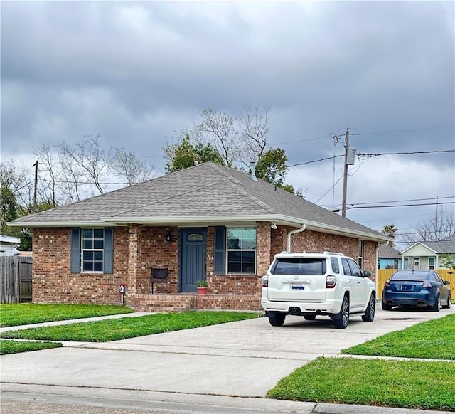 view of front of house with brick siding, concrete driveway, a front lawn, and fence