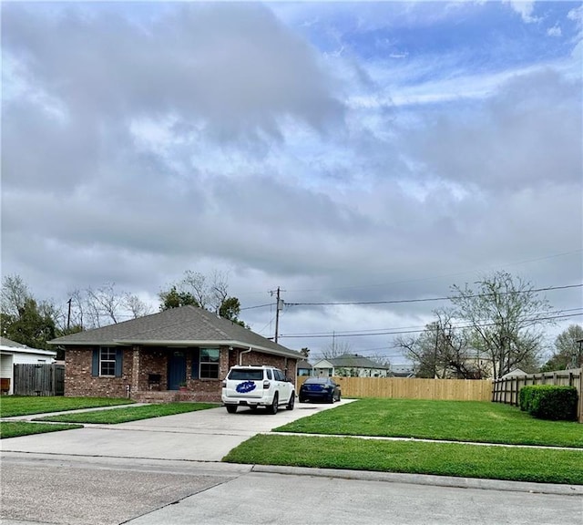 view of front of property featuring brick siding, concrete driveway, fence, and a front yard
