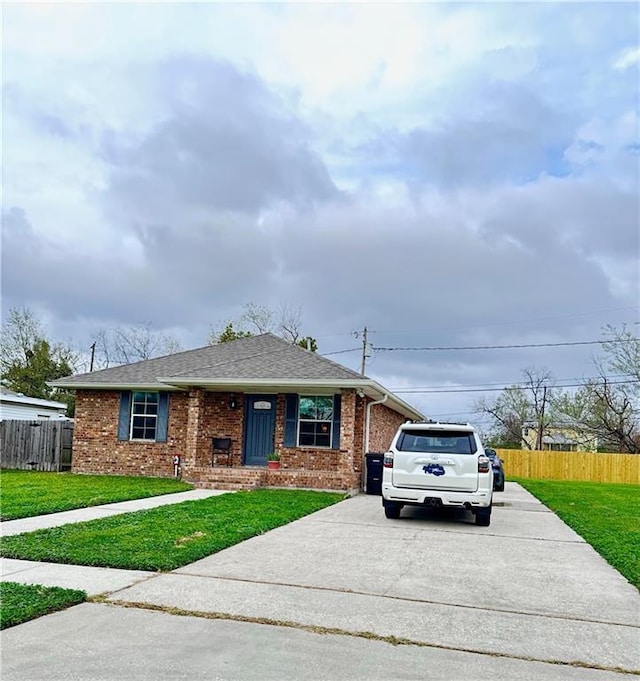 ranch-style home featuring driveway, brick siding, and a front yard