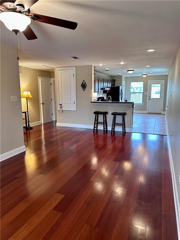 living area featuring visible vents, baseboards, wood finished floors, and a ceiling fan