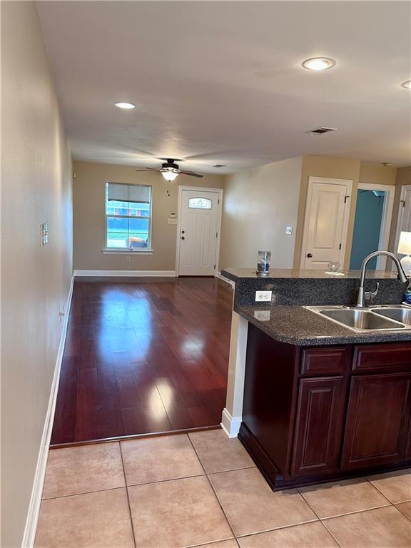 kitchen featuring a sink, baseboards, ceiling fan, and light tile patterned floors