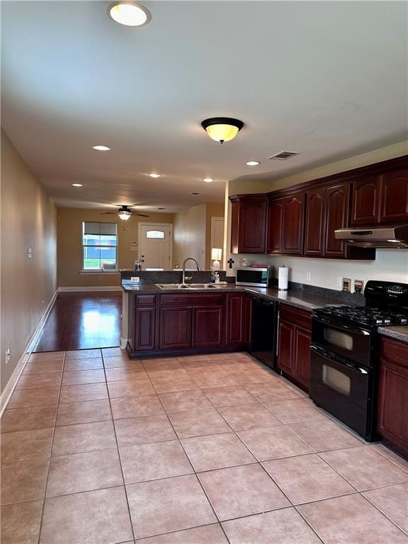 kitchen featuring visible vents, black appliances, under cabinet range hood, a sink, and dark countertops
