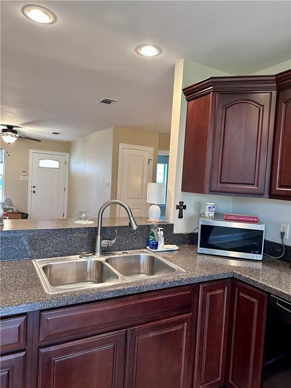 kitchen featuring dark countertops, ceiling fan, a sink, dishwasher, and stainless steel microwave