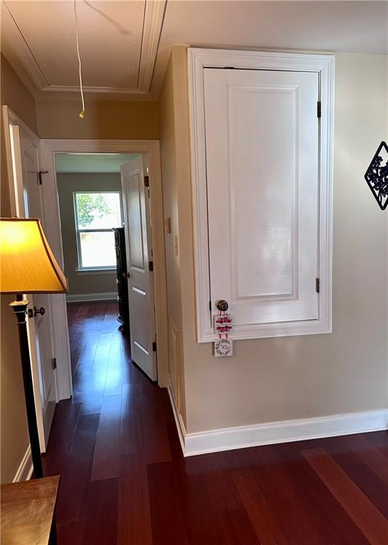 hall with baseboards, attic access, and dark wood finished floors
